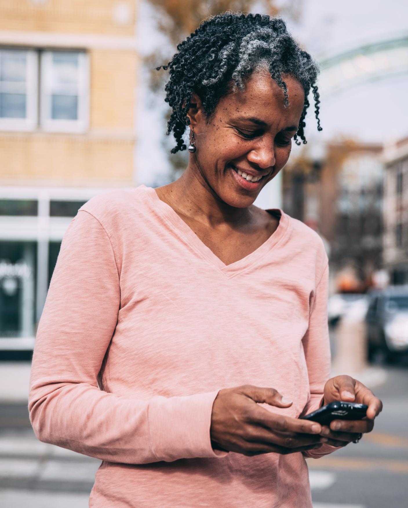 Woman stands outside texting on phone